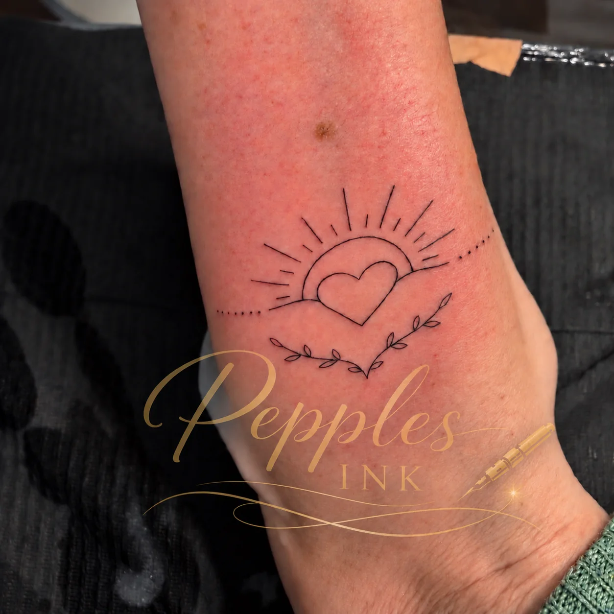 Fine Line Tattoo mit Herz, Sonne und feinem Pflanzenzweig